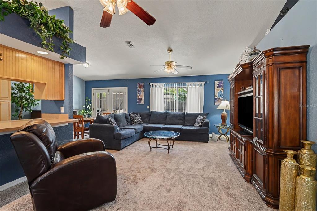 A living room features blue walls, a large sectional sofa, a recliner, and a wooden entertainment center — 35 PLANTATION ROAD, DEBARY, FL