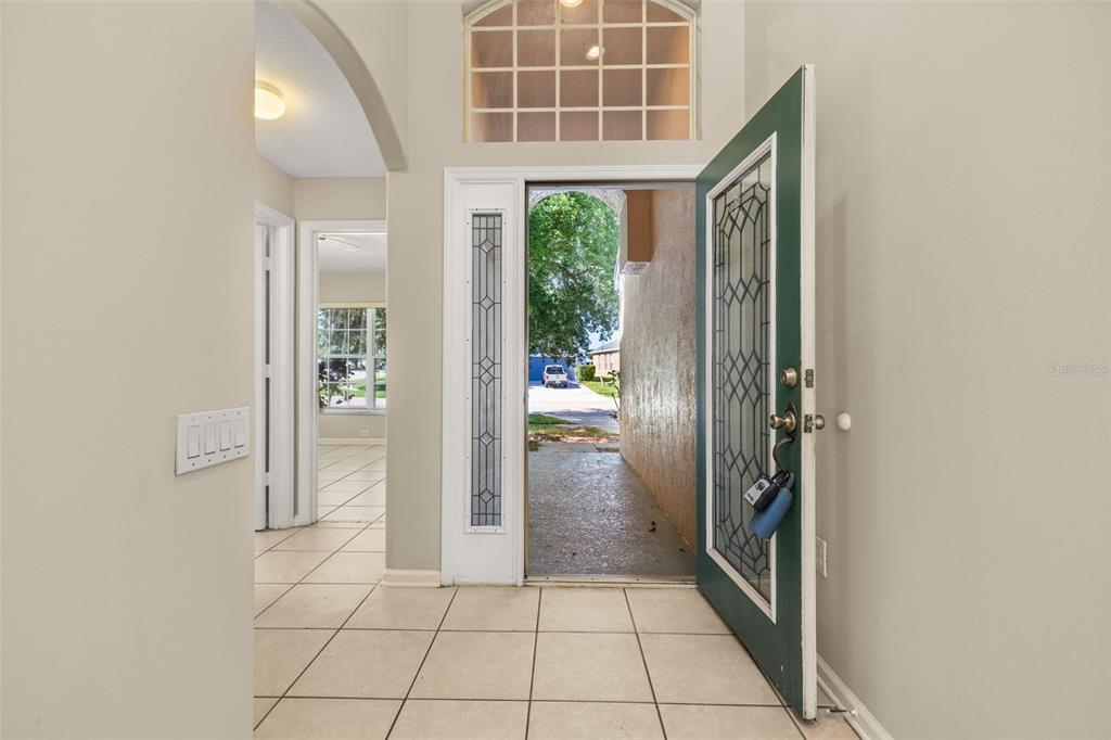 An entryway with tiled floors, a green front door, and a view of the driveway — 3145 STONEHURST CIRCLE, KISSIMMEE, FL
