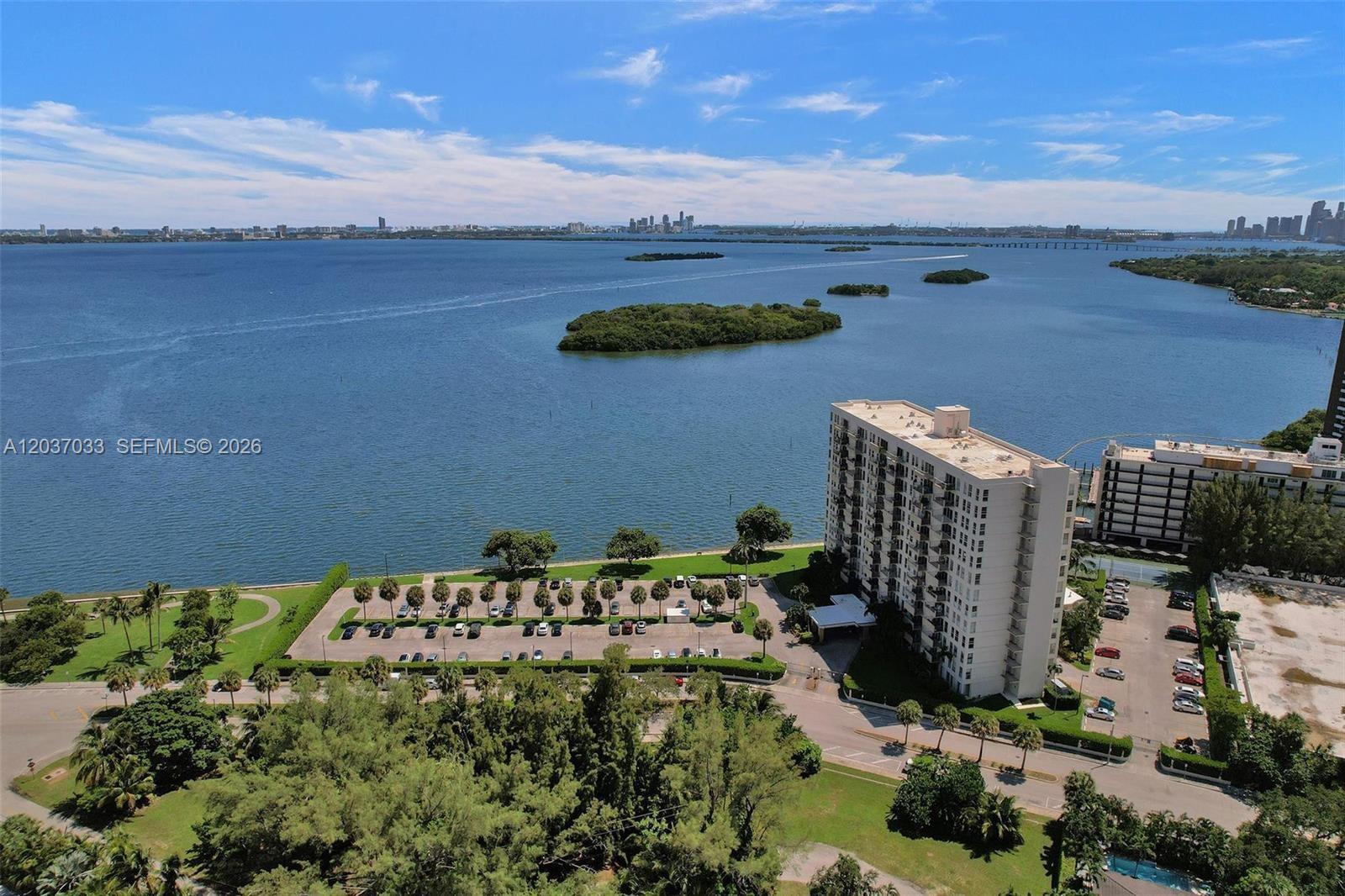 An aerial view shows a waterfront apartment building with a parking lot and surrounding trees — 765 NE 70TH ST, Miami FL 33138, MIAMI, FL