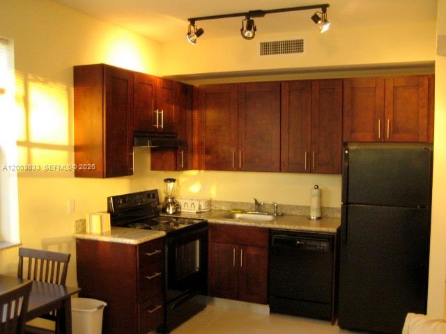 A kitchen features dark wood cabinets, black appliances, and a track lighting fixture — 843 SW 13th Ave # 202, Miami FL 33135, MIAMI, FL