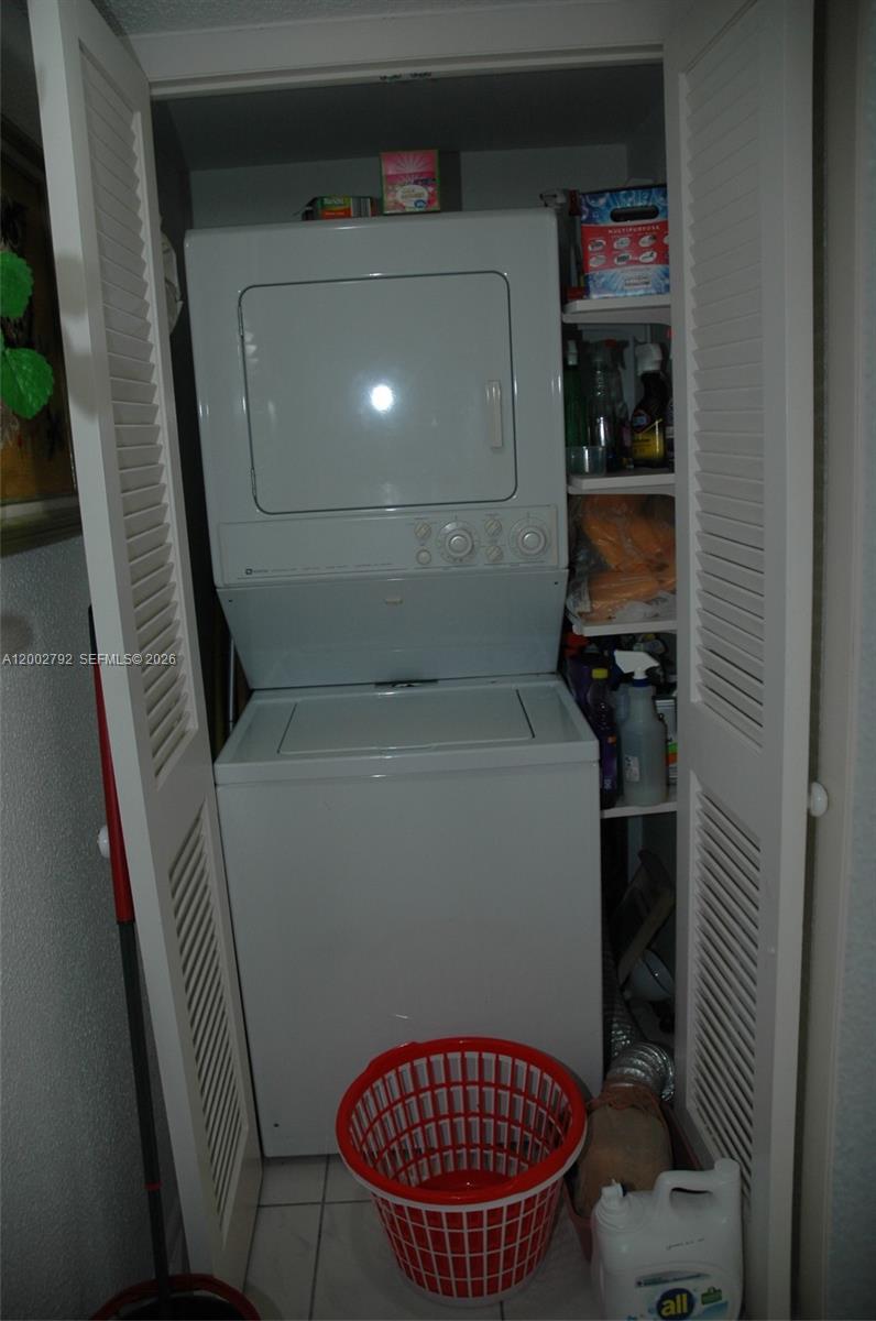 A white stacked washer and dryer unit sits inside a closet with louvered doors — 1401 S Ocean Blvd # 408, Pompano Beach FL 33062, POMPANO BEACH, FL