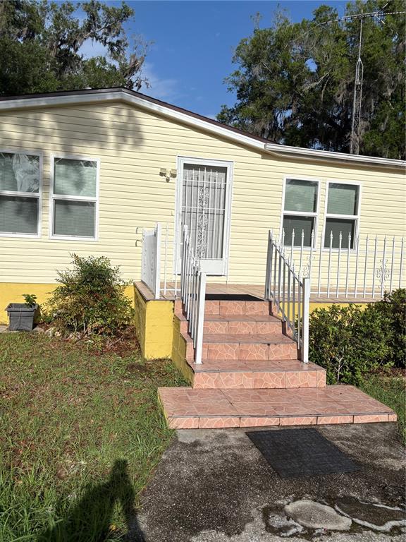 A yellow mobile home features a tiled front staircase with white metal railings — 14490 SE 80TH AVENUE, SUMMERFIELD, FL