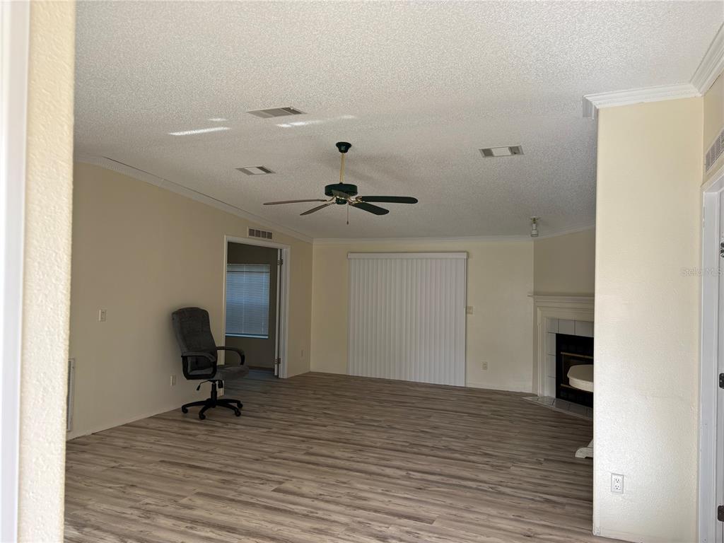 A living room with light wood-look flooring, a ceiling fan, and a corner fireplace — 14490 SE 80TH AVENUE, SUMMERFIELD, FL