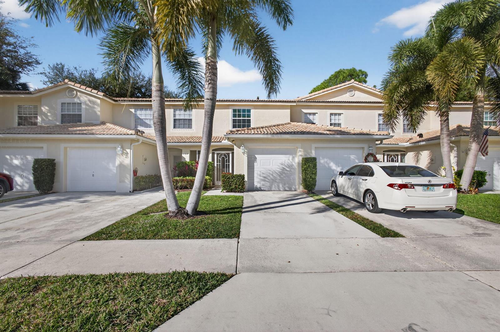 A row of two-story townhouses with beige stucco exteriors, tile roofs, and attached garages — 106 Wooden Mill Terrace, Jupiter FL 33458, JUPITER, FL