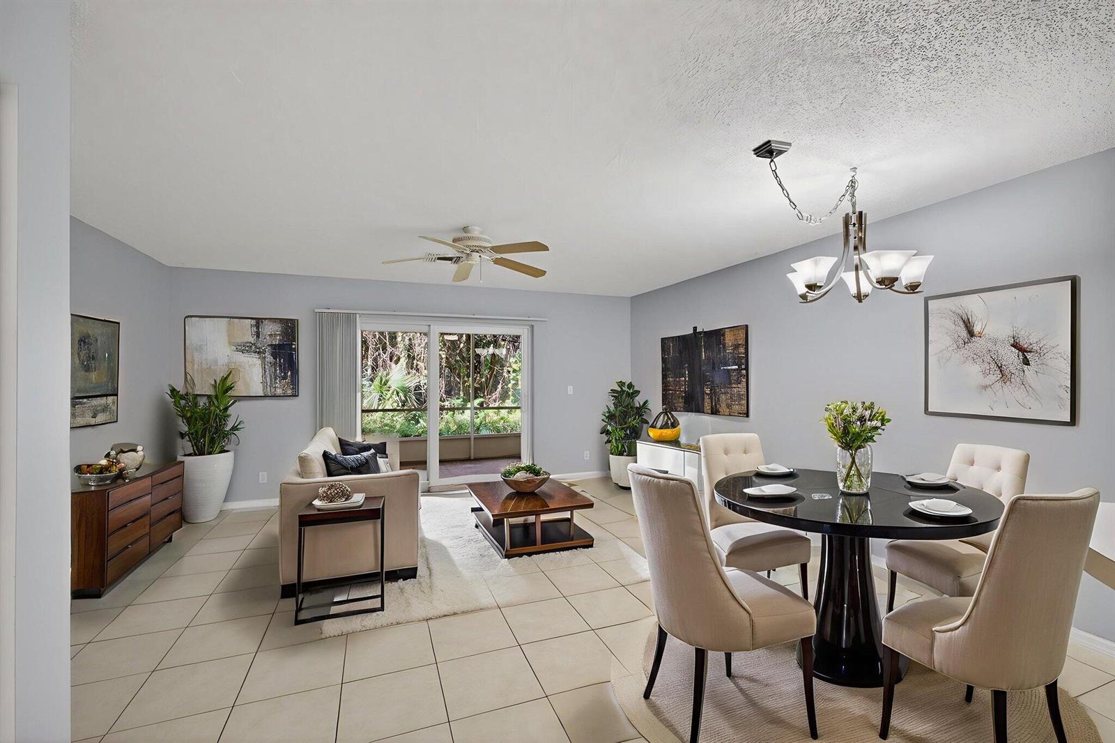 An open-concept living and dining area features light gray walls, tile floors, and sliding doors — 106 Wooden Mill Terrace, Jupiter FL 33458, JUPITER, FL
