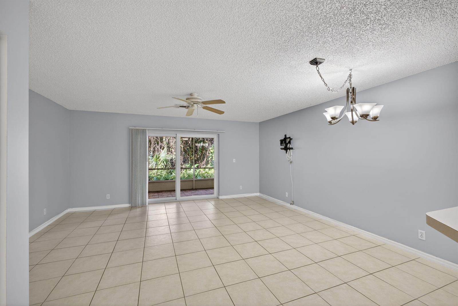 An empty room with light gray walls, beige tile flooring, a ceiling fan, and sliding doors — 106 Wooden Mill Terrace, Jupiter FL 33458, JUPITER, FL