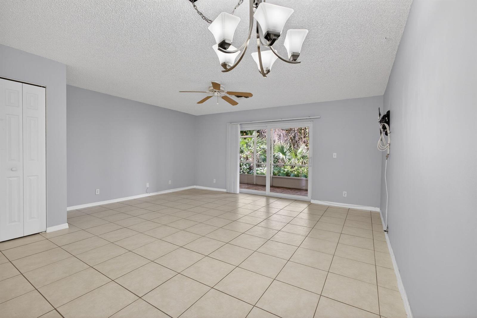 An empty room with light gray walls, tile flooring, a ceiling fan, and sliding glass doors — 106 Wooden Mill Terrace, Jupiter FL 33458, JUPITER, FL