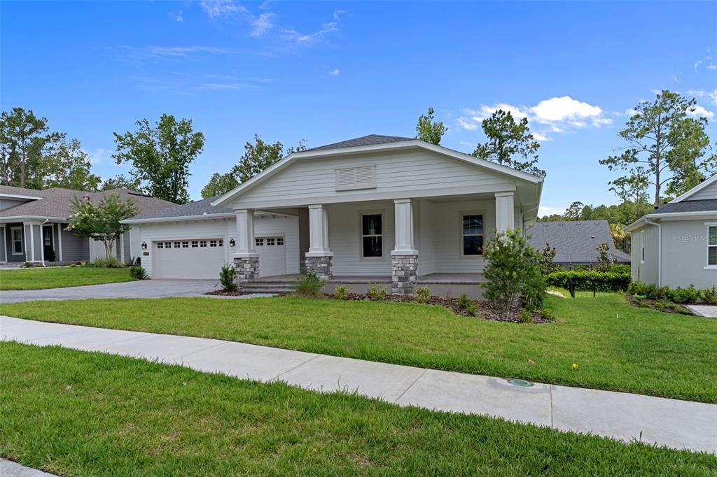 A single-story house with a white exterior, stone-based columns, and a front porch — 4538 MAJESTIC HILLS LOOP, BROOKSVILLE, FL