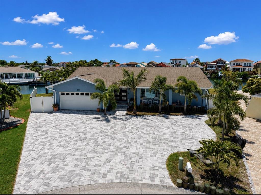 A light blue house exterior features a paved walkway, a covered porch, and palm trees — 6301 COTTONWOOD LANE, APOLLO BEACH, FL