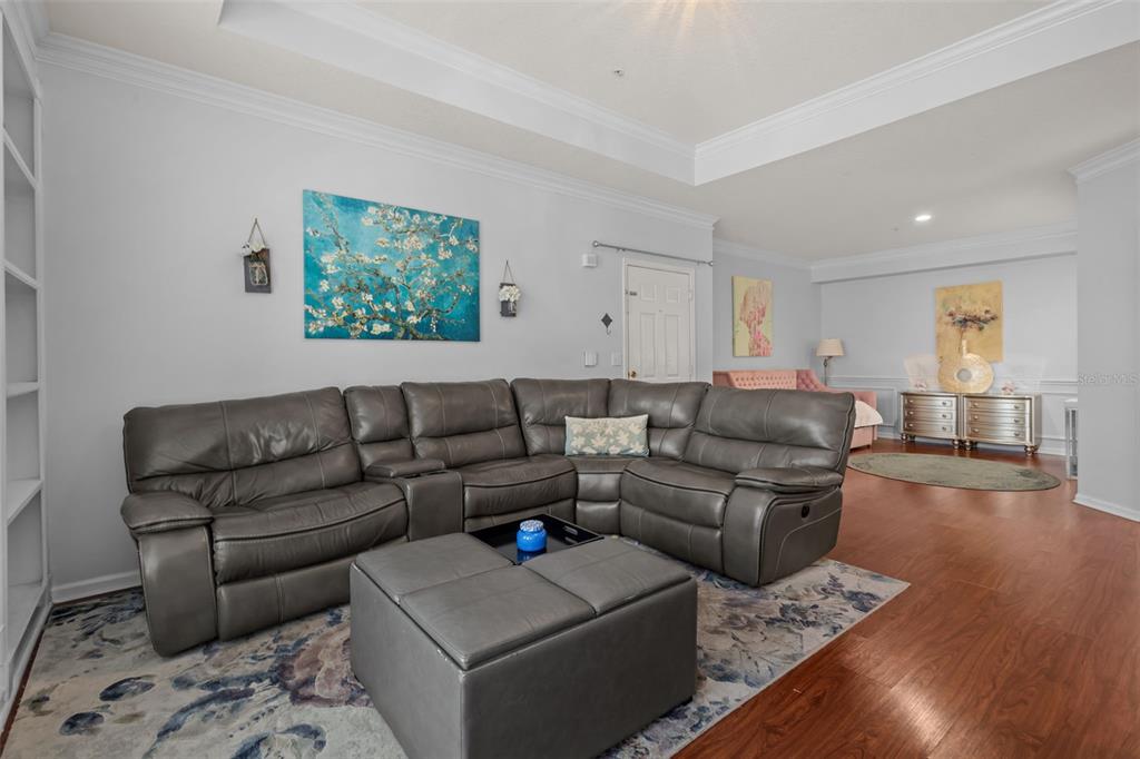 A living room features a grey leather sectional sofa, a matching ottoman, and hardwood floors — 3302 BAY CLUB CIRCLE UNIT 3202, TAMPA, FL