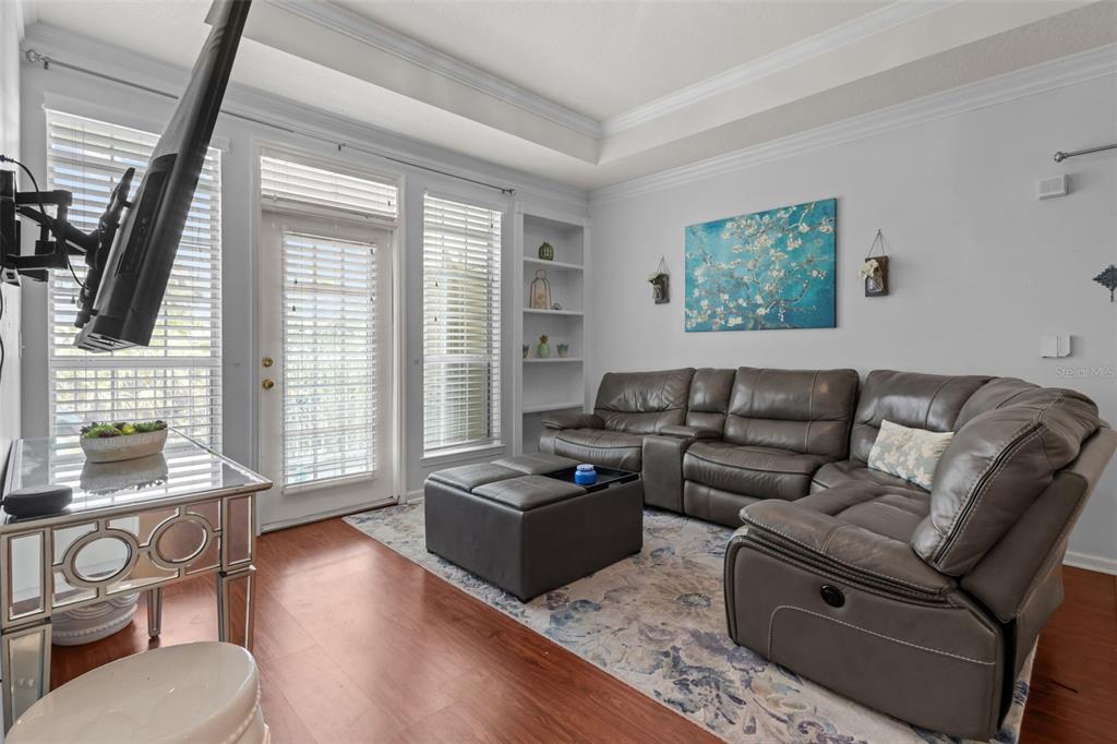 A living room features a grey sectional sofa, a matching ottoman, and a glass-topped table — 3302 BAY CLUB CIRCLE UNIT 3202, TAMPA, FL