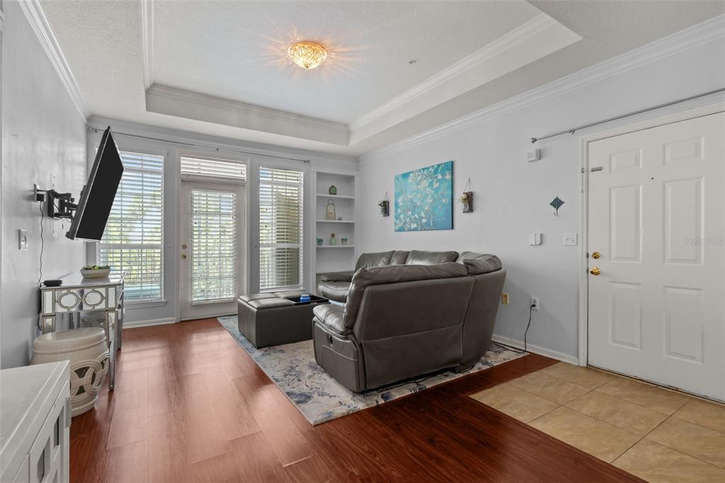 A living room with wood flooring, a gray leather sofa, and a white front door — 3302 BAY CLUB CIRCLE UNIT 3202, TAMPA, FL