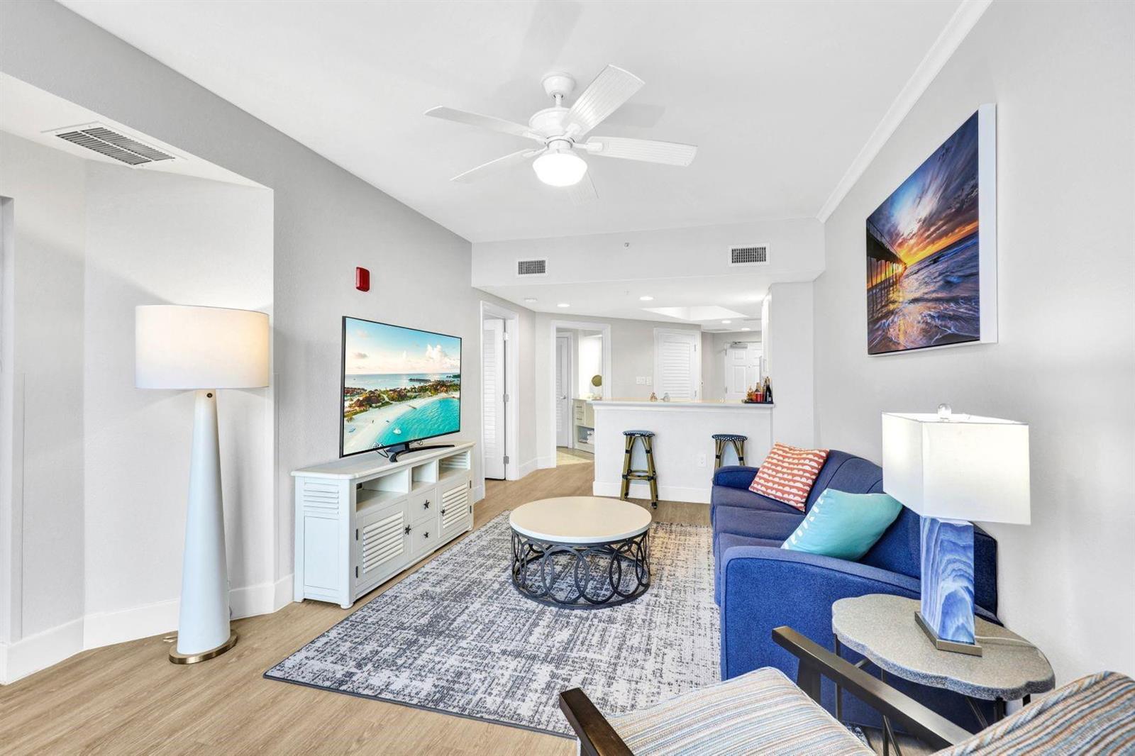 A living room features a blue sofa, a white media console, and a ceiling fan — 200 Estero Boulevard # 207, FL 33931, FL