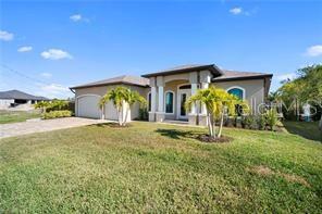 A single-story house with a paved driveway, a three-car garage, and a dark wooden fence — 2341 NW 36TH PLACE, CAPE CORAL, FL