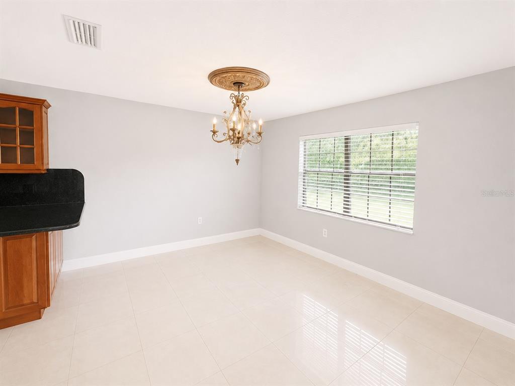 A dining area with light tile floors, a chandelier, and a window with blinds — 7126 SHEFFIELD DRIVE, LAKELAND, FL