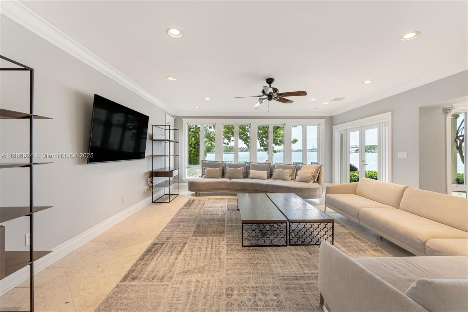 A living room features a curved sofa, a white sofa, and a view of water — 11 E Rivo Alto Dr, Miami Beach FL 33139, MIAMI BEACH, FL