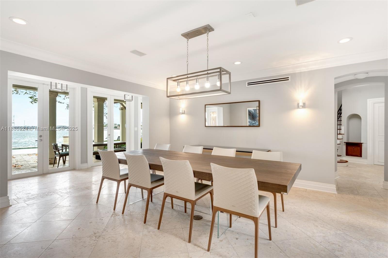 A dining room features a long wooden table, white chairs, and a rectangular light fixture — 11 E Rivo Alto Dr, Miami Beach FL 33139, MIAMI BEACH, FL