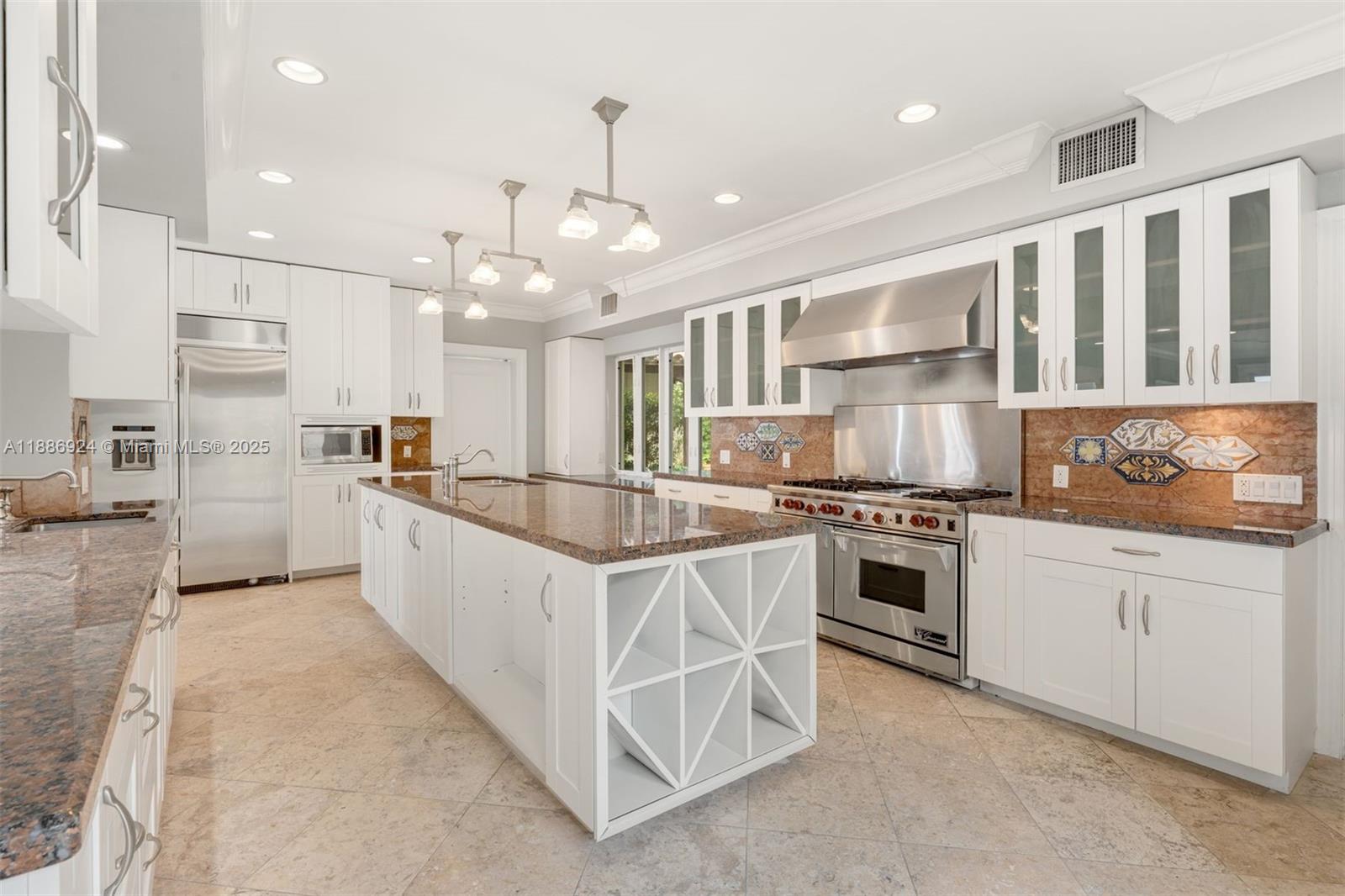 A white kitchen features a large granite-topped island, stainless steel appliances, and tile flooring — 11 E Rivo Alto Dr, Miami Beach FL 33139, MIAMI BEACH, FL