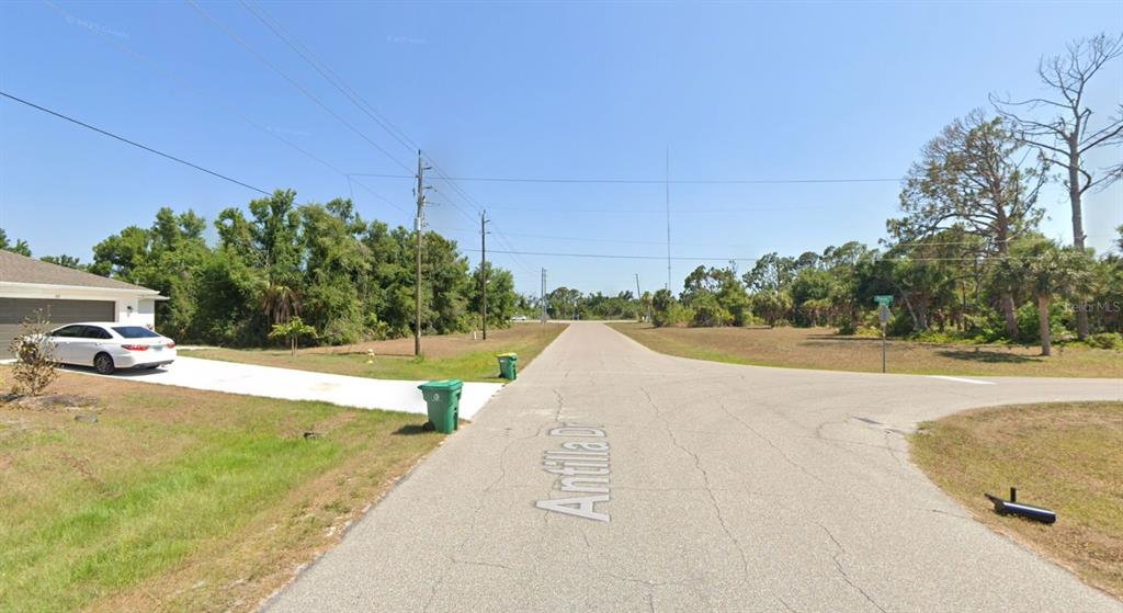 A paved street intersection with a white car parked in a residential driveway — 107 ANTILLA DRIVE, ROTONDA WEST, FL