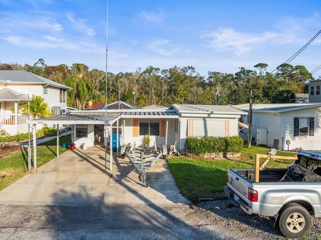 A single-story house with a metal carport and a boat trailer parked in the driveway — 7260 ABERDEEN COURT, WEEKI WACHEE, FL