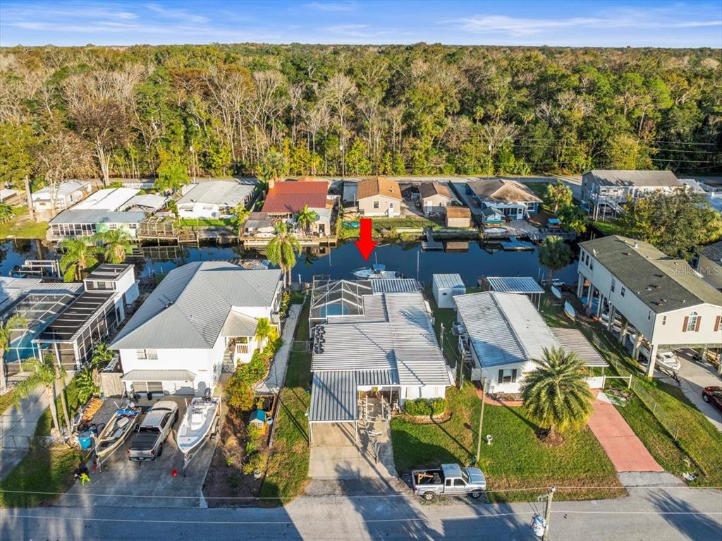 An aerial view shows several waterfront homes with boat docks along a narrow canal — 7260 ABERDEEN COURT, WEEKI WACHEE, FL