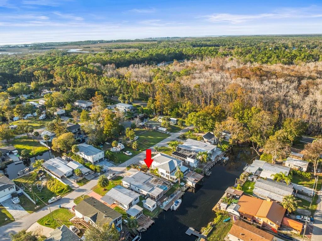 An aerial view shows a waterfront house with a red arrow pointing to its roof — 7260 ABERDEEN COURT, WEEKI WACHEE, FL