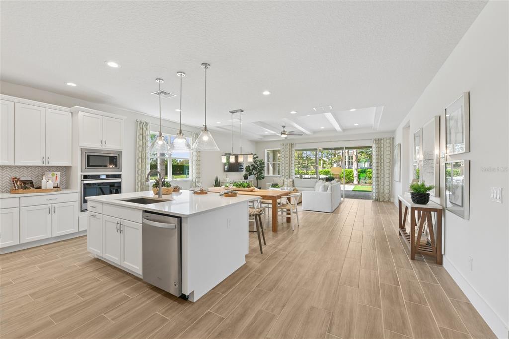 A bright, open-concept kitchen and living area features white cabinetry, a large island, and tile — 2418 PARK RIDGE STREET, APOPKA, FL