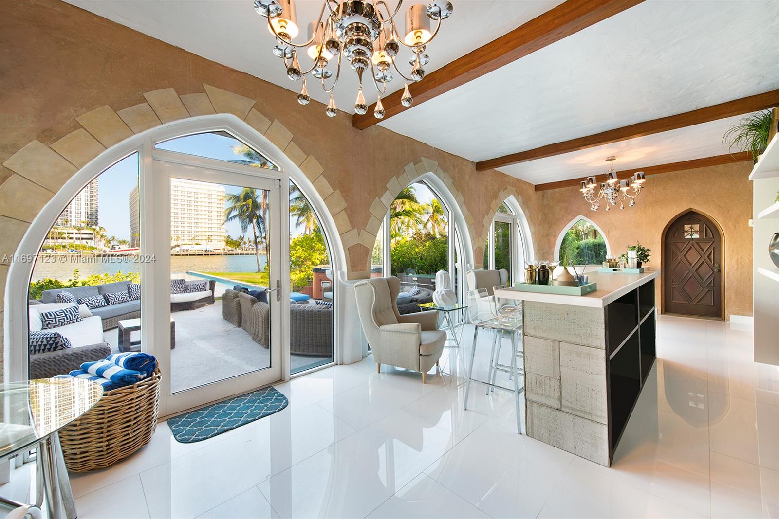 A bright living area features arched glass doors, stone-textured walls, a bar, and waterfront views — 4745 Pine Tree Dr, Miami Beach FL 33140, MIAMI BEACH, FL