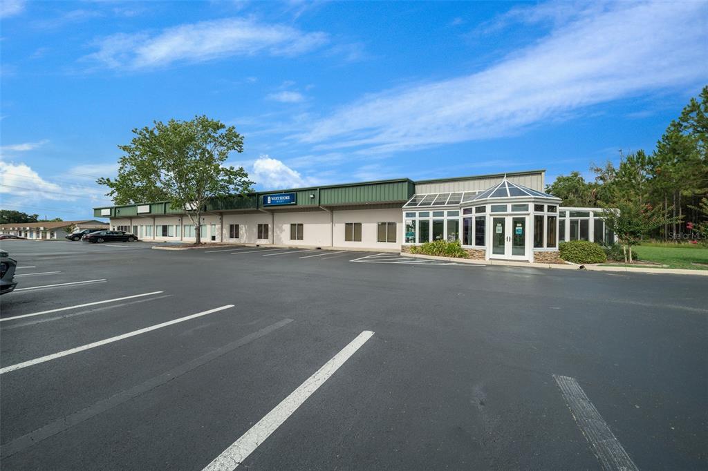 A single-story commercial building with a large parking lot and a glass-enclosed entrance — 1720 NW 4TH AVENUE All Units, OCALA, FL