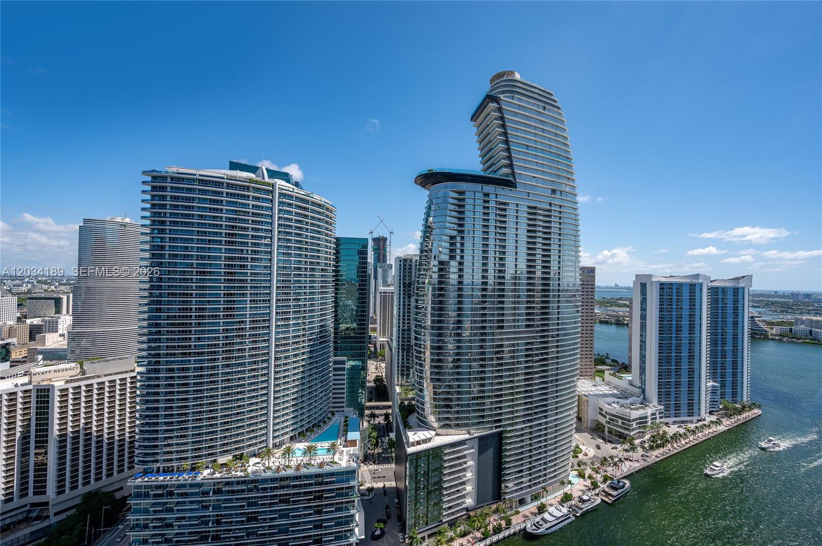 An aerial view shows several modern high-rise buildings and a waterfront in a city — 475 Brickell Ave # 4115, Miami FL 33131, MIAMI, FL
