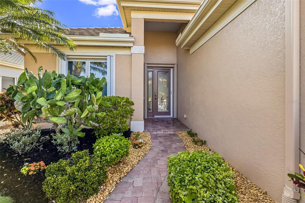 A paved walkway leads to a front entrance with a glass door and desert landscaping — 5231 97TH STREET E, BRADENTON, FL