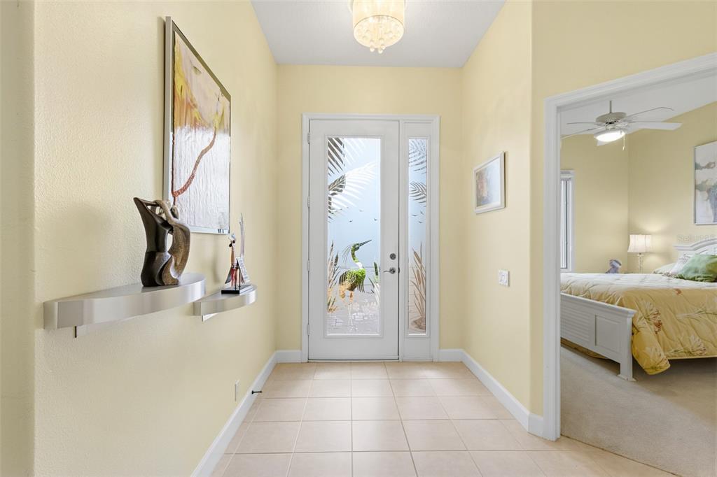 A bright entryway features light-colored tile flooring, pale yellow walls, and a glass-paneled front door — 5231 97TH STREET E, BRADENTON, FL