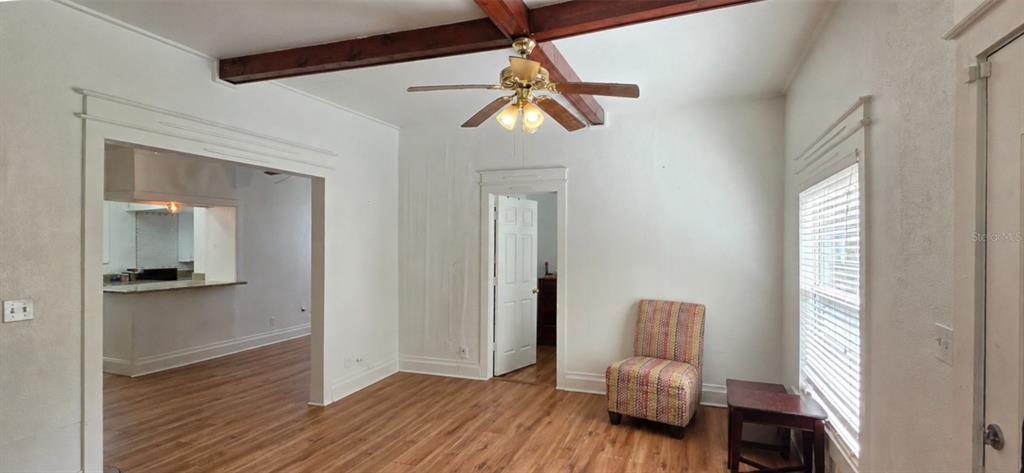 A living room features wood-look flooring, a ceiling fan with exposed beams, and a doorway — 8211 N 10TH STREET, TAMPA, FL