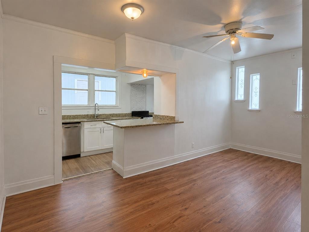 A kitchen with white cabinets and a granite breakfast bar opens into a dining area — 8211 N 10TH STREET, TAMPA, FL