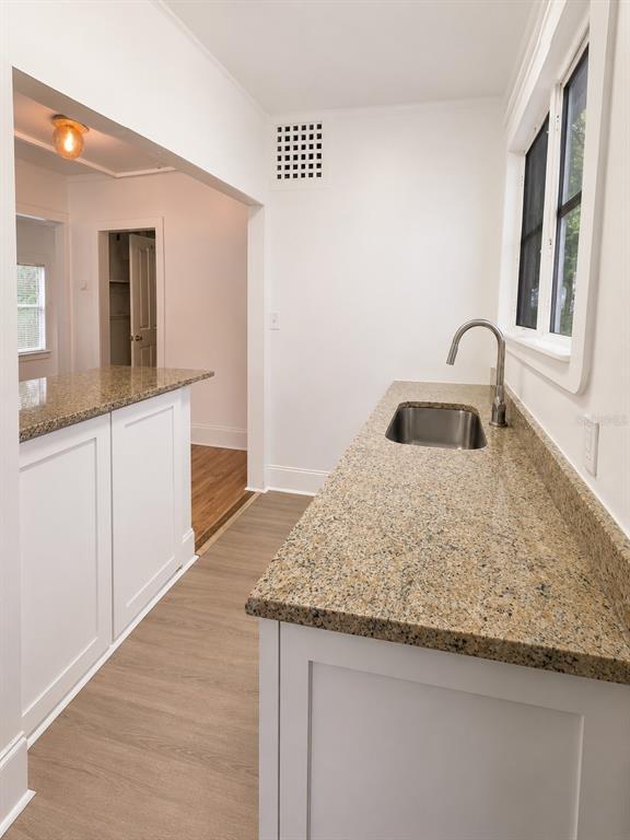 A kitchen area features white cabinets, granite countertops, a stainless steel sink, and wood flooring — 8211 N 10TH STREET, TAMPA, FL