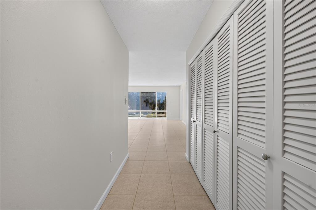 A hallway with light tile flooring leads to a living area with large windows — 700 MELROSE AVENUE UNIT A5, WINTER PARK, FL