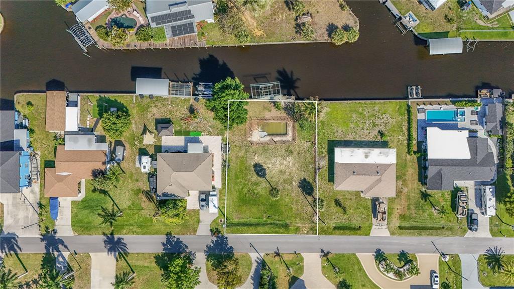 An aerial view shows a vacant waterfront lot with a small pool between two houses — 116 E NORTH SHORE AVENUE, NORTH FORT MYERS, FL