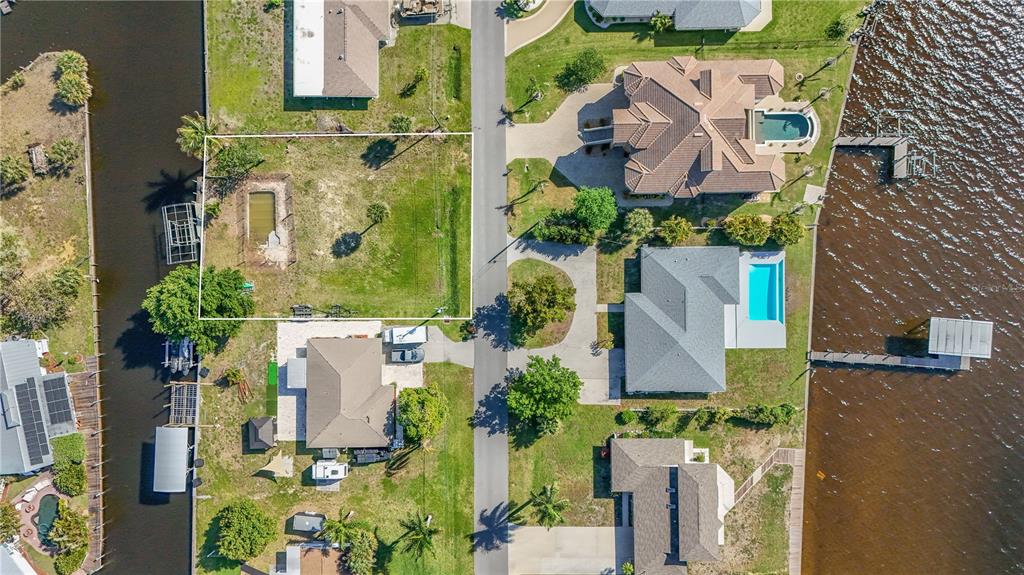 An aerial view shows a vacant residential lot outlined in white next to a paved road — 116 E NORTH SHORE AVENUE, NORTH FORT MYERS, FL