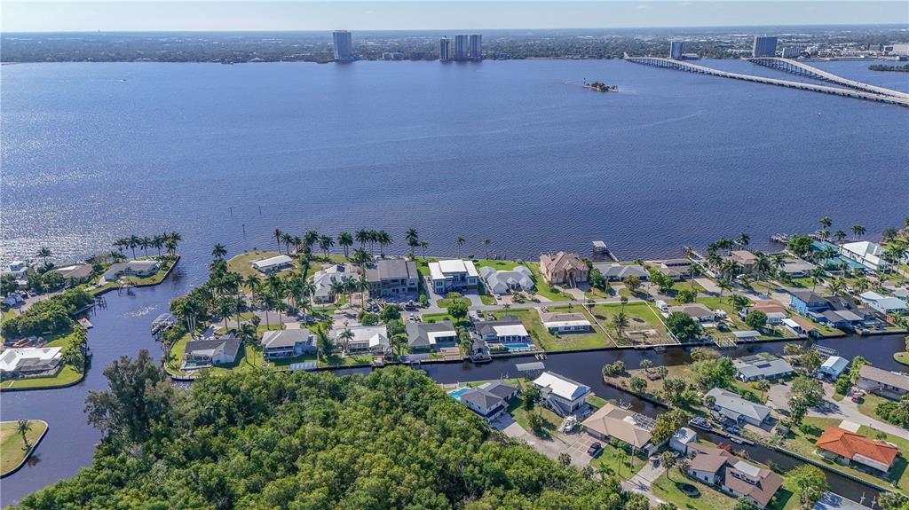 An aerial view of waterfront homes along a canal with a large bridge in the distance — 116 E NORTH SHORE AVENUE, NORTH FORT MYERS, FL