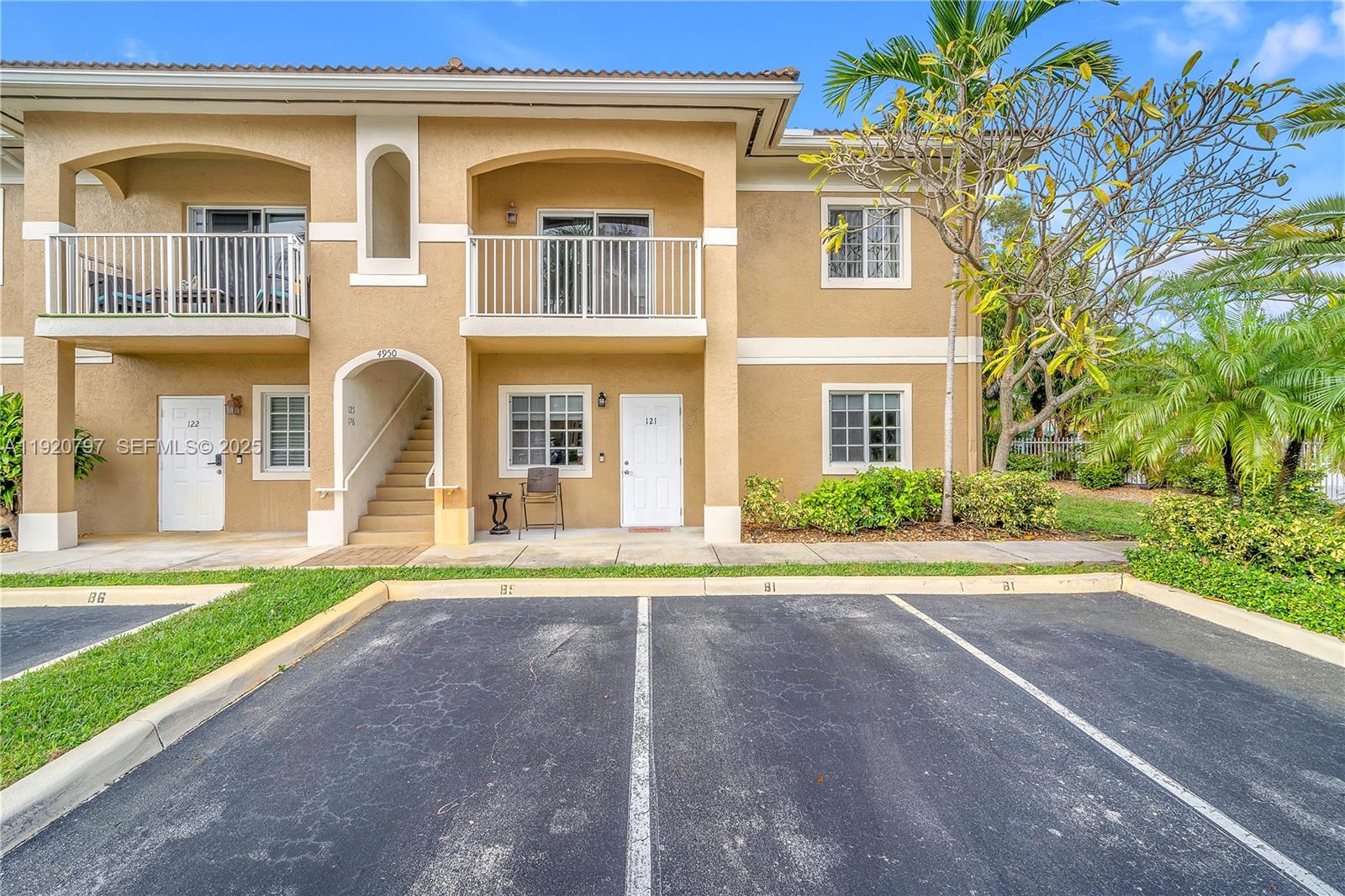A two-story tan stucco apartment building with white railings and assigned parking spaces in front — 4950 Washington St # 1, Hollywood FL 33021, HOLLYWOOD, FL
