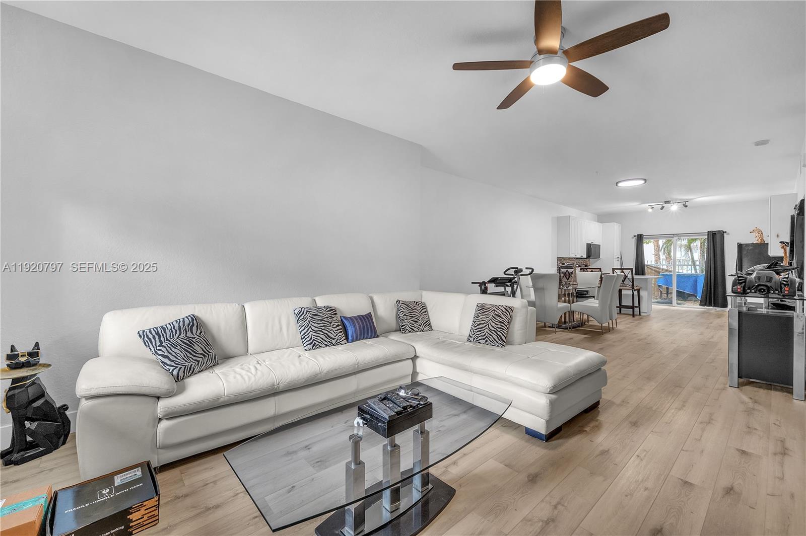 A living room features a white sectional sofa, glass coffee table, and light wood flooring — 4950 Washington St # 1, Hollywood FL 33021, HOLLYWOOD, FL