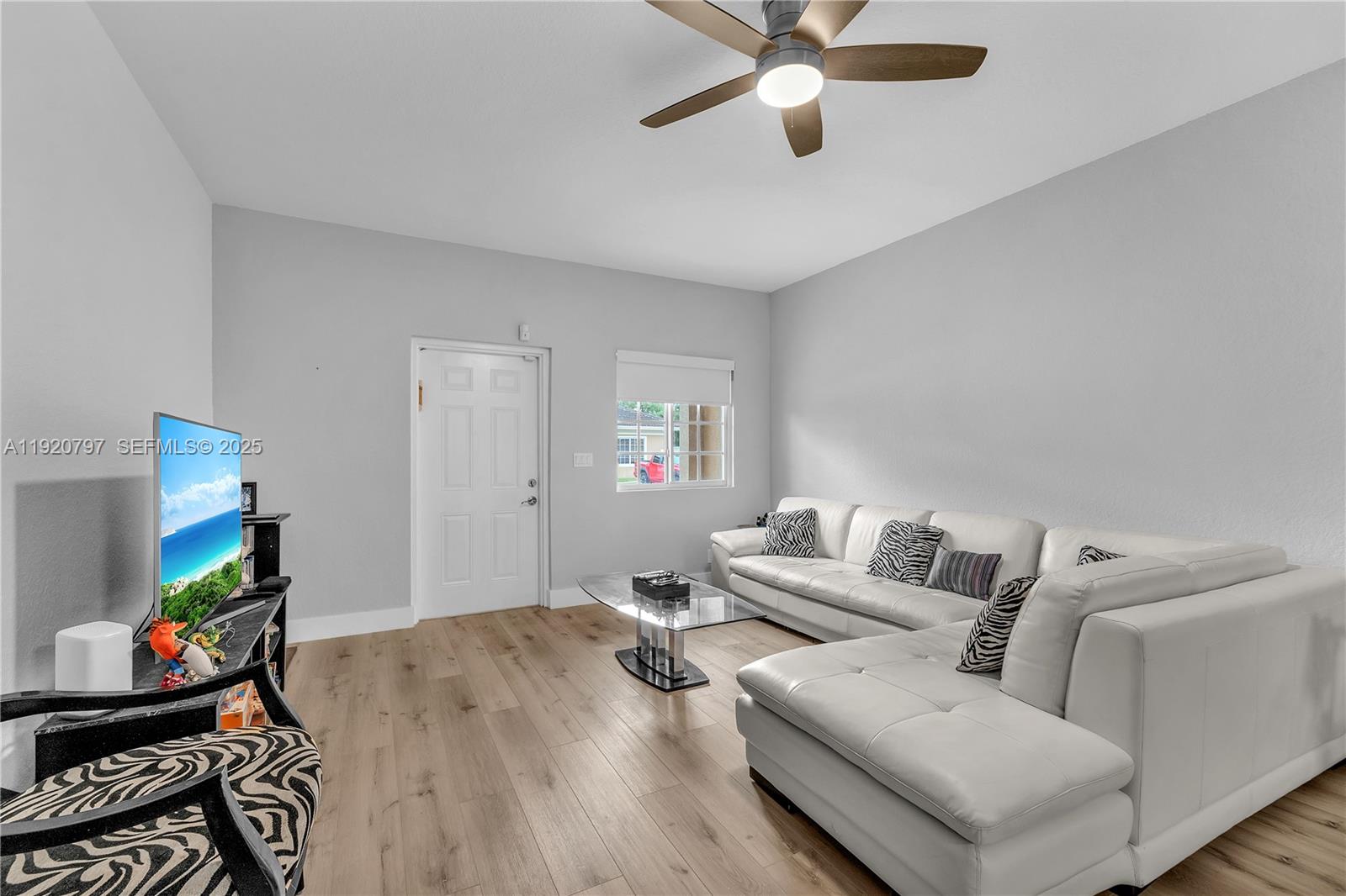 A living room features a white sectional sofa, glass coffee table, and light wood flooring — 4950 Washington St # 1, Hollywood FL 33021, HOLLYWOOD, FL
