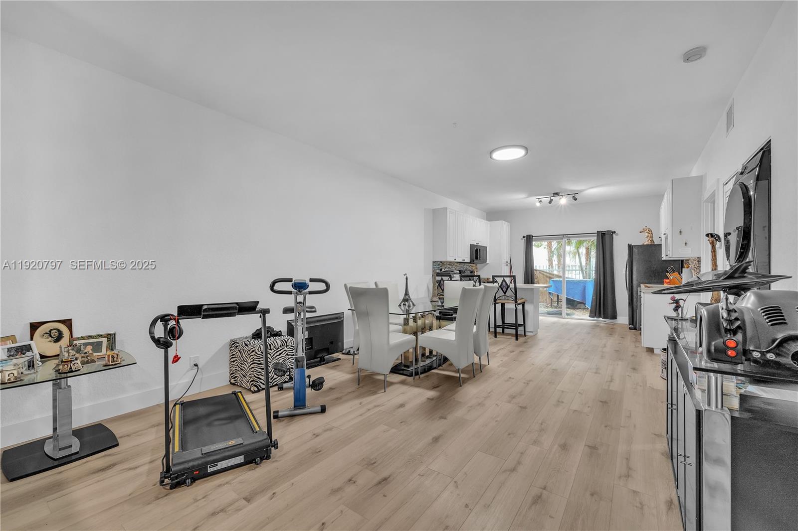 This open-concept living area features a dining set, exercise equipment, and a kitchen — 4950 Washington St # 1, Hollywood FL 33021, HOLLYWOOD, FL