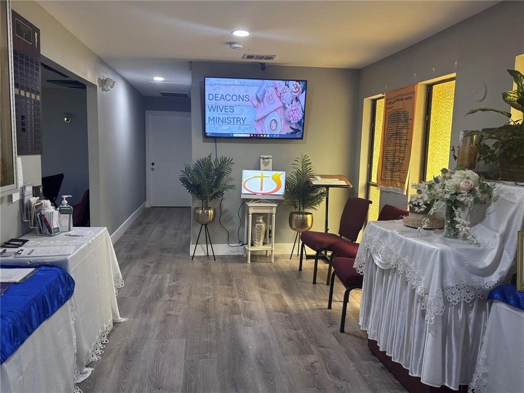 A church interior features a television screen, tables with white cloths, and maroon chairs — 2270 JUPITER BLVD, PALM BAY, FL