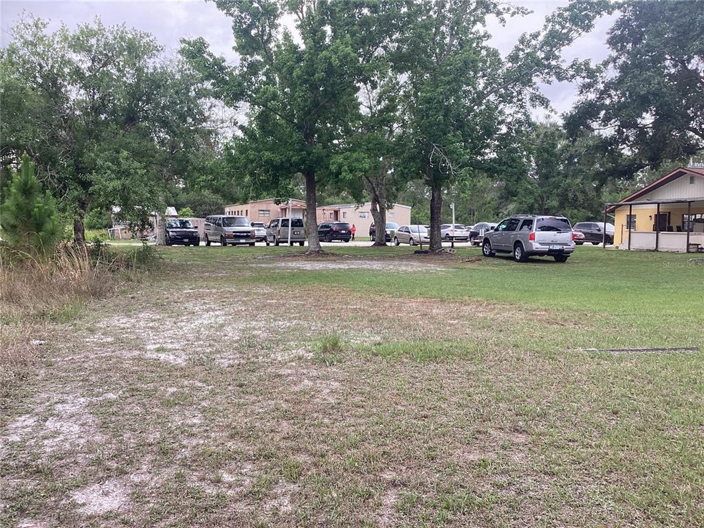 A grassy, partially sandy lot with several parked cars and trees in the background — 2270 JUPITER BLVD, PALM BAY, FL