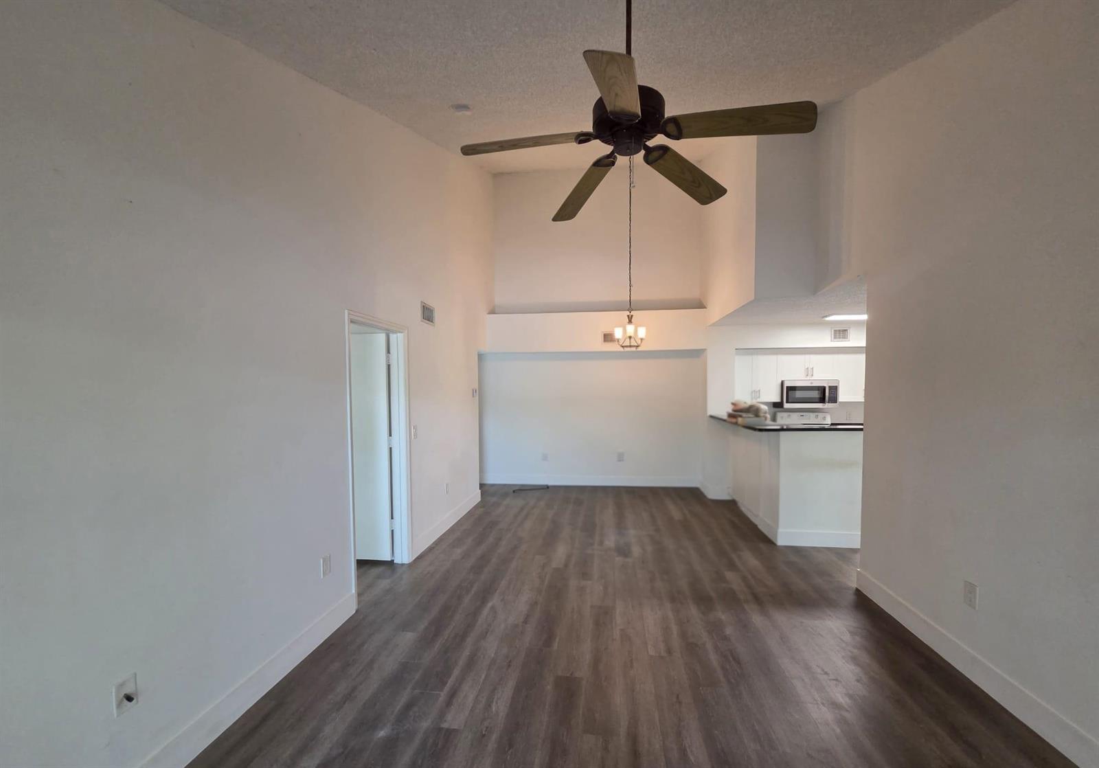 An open living area features high ceilings, a ceiling fan, and wood-look flooring — 12112 St.andrews Place # 212, Miramar FL 33025, MIRAMAR, FL