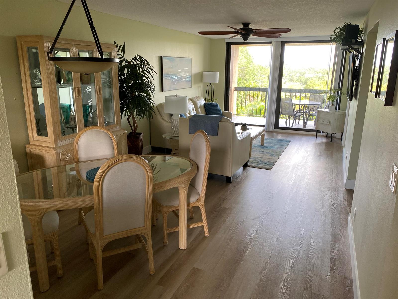 A dining area and living room with light wood flooring, a glass table, and balcony access — 600 Egret Circle # 7401, Delray Beach FL 33444, DELRAY BEACH, FL