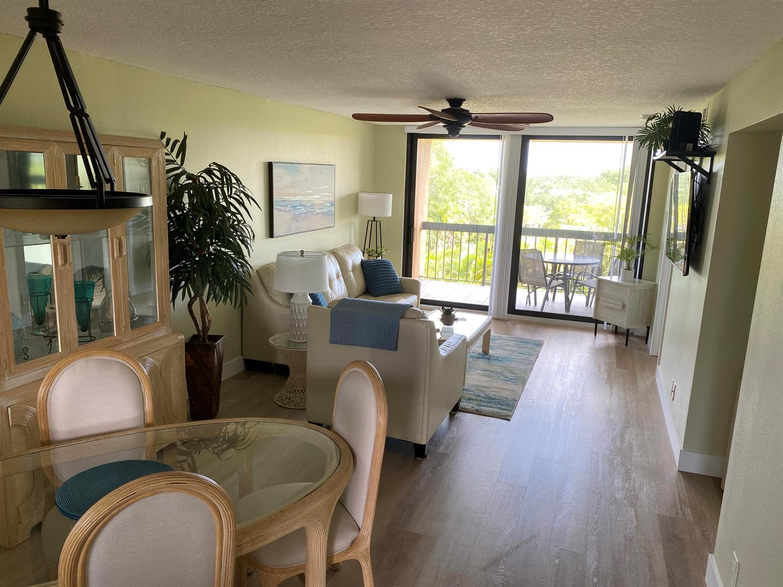 A living and dining area with light wood floors, neutral furniture, and a balcony view — 600 Egret Circle # 7401, Delray Beach FL 33444, DELRAY BEACH, FL