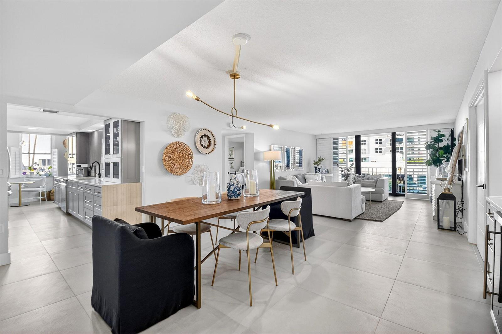 An open-concept living and dining area features a wooden table, modern lighting, and tile flooring — 3456 S Ocean Boulevard # 105, Palm Beach FL 33480, PALM BEACH, FL