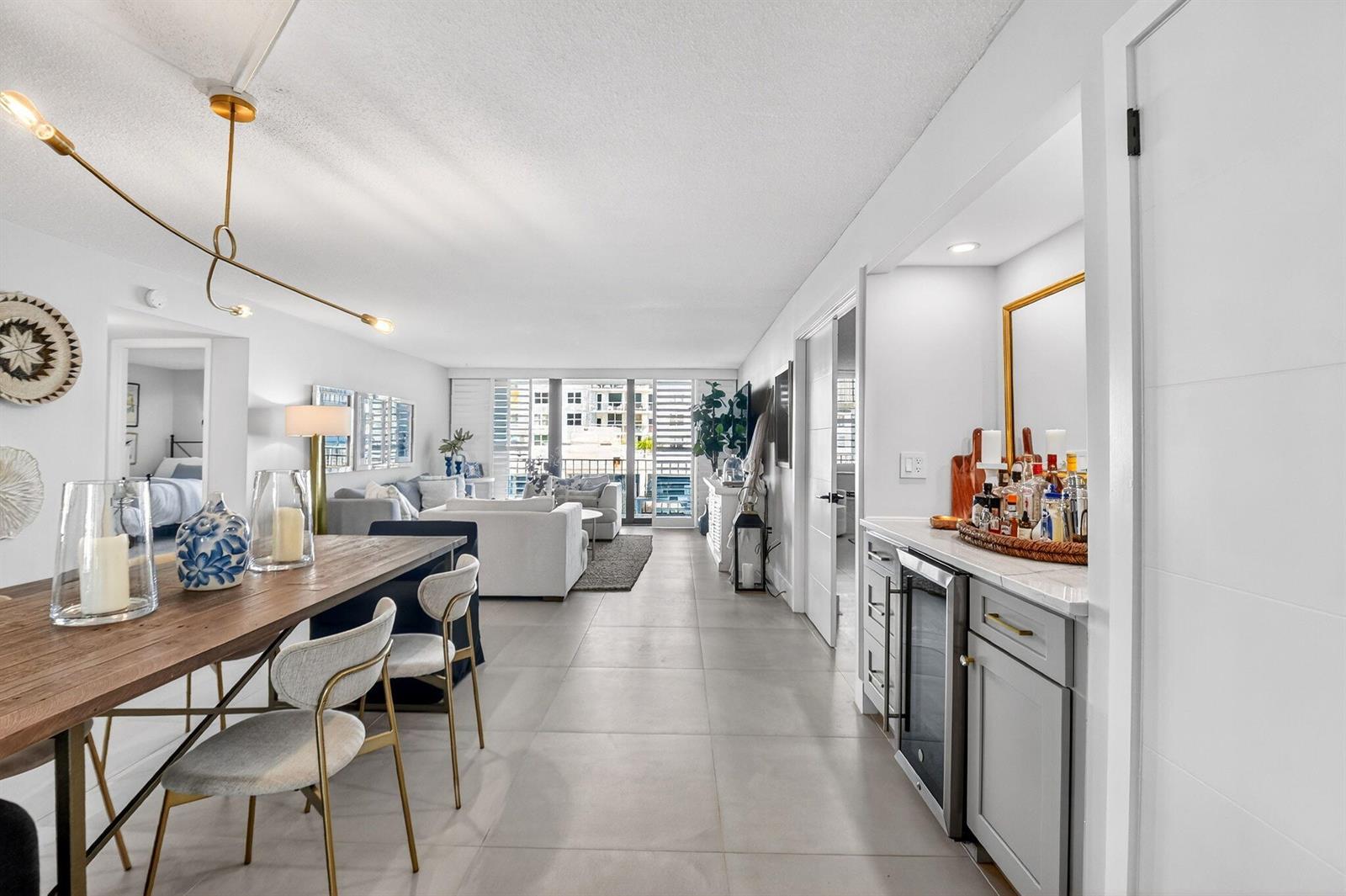 A bright open-concept living and dining area features tile floors, a wet bar, and balcony — 3456 S Ocean Boulevard # 105, Palm Beach FL 33480, PALM BEACH, FL